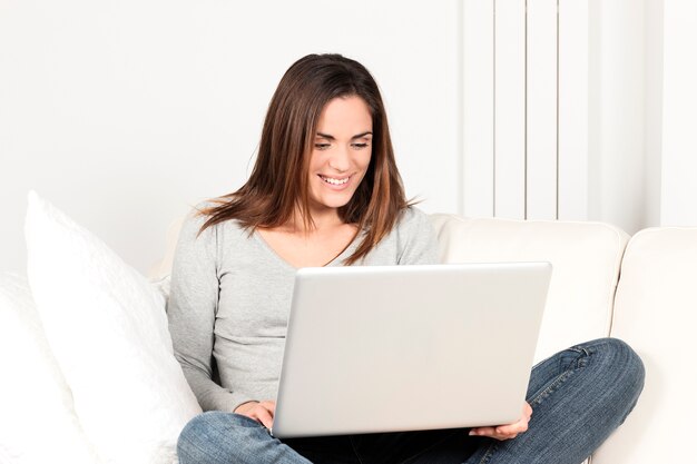 Hermosa mujer usando laptop en sofá