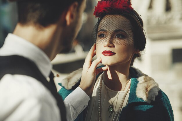 Hermosa mujer vestida de estilo años 30 se encuentra en la calle y mira a su hombre con amor