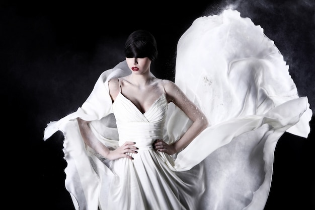 Hermosa mujer en vestido blanco y polvo volador