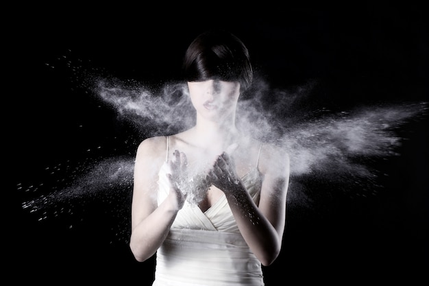 Hermosa mujer en vestido blanco y polvo volador