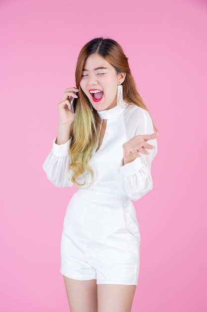 Hermosa mujer, vestido blanco que muestra el teléfono y el estado de ánimo de la cara.