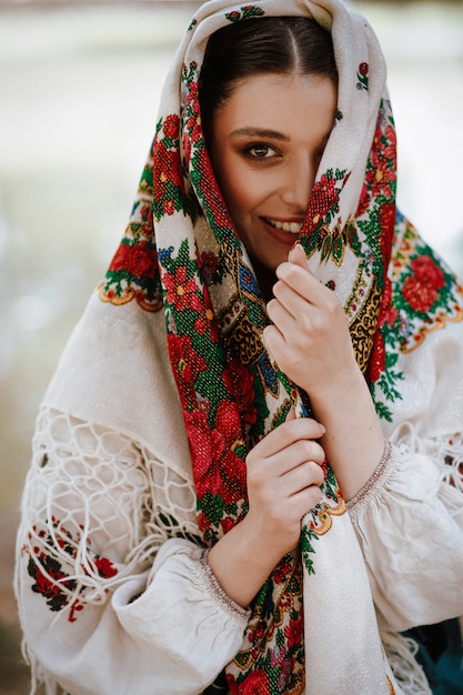 Hermosa mujer en un vestido étnico tradicional con una capa bordada en la cabeza sonriendo