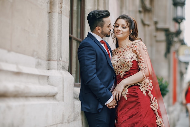 Hermosa mujer en un vestido largo rojo camina por la ciudad con su marido