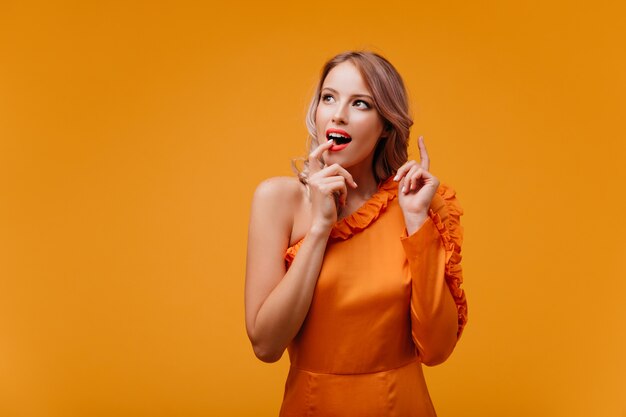 Hermosa mujer en vestido naranja expresando asombro