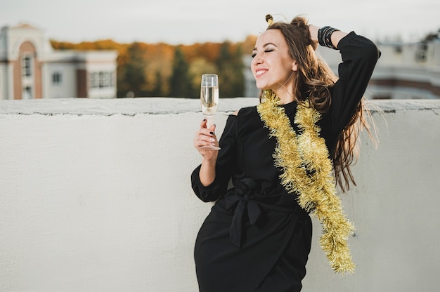 Hermosa mujer en vestido negro admirando la vista desde la azotea