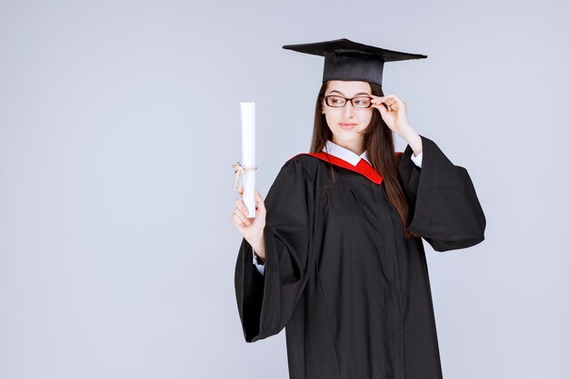 Hermosa mujer en vestido sosteniendo su diploma universitario. Foto de alta calidad