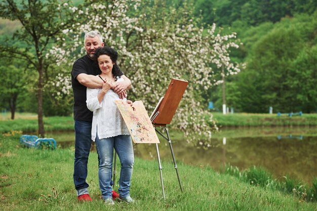 Hermosa naturaleza. Pareja madura tiene días de ocio y trabajando juntos en la pintura en el parque