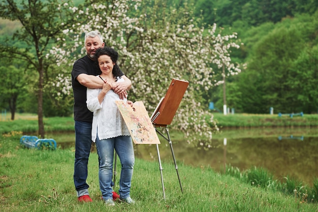 Hermosa naturaleza. Pareja madura tiene días de ocio y trabajando juntos en la pintura en el parque