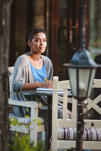 Hermosa niña africana escribiendo en el cuaderno