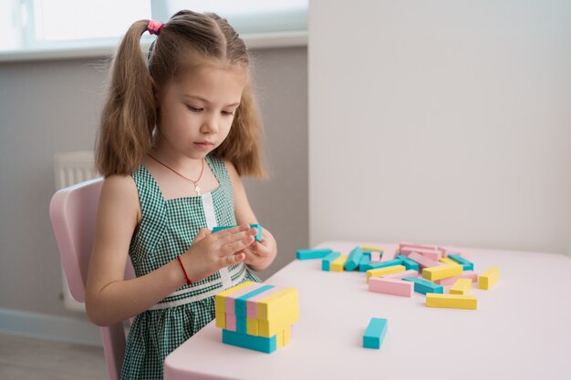 Hermosa niña caucásica jugando con bloques multicolores de madera