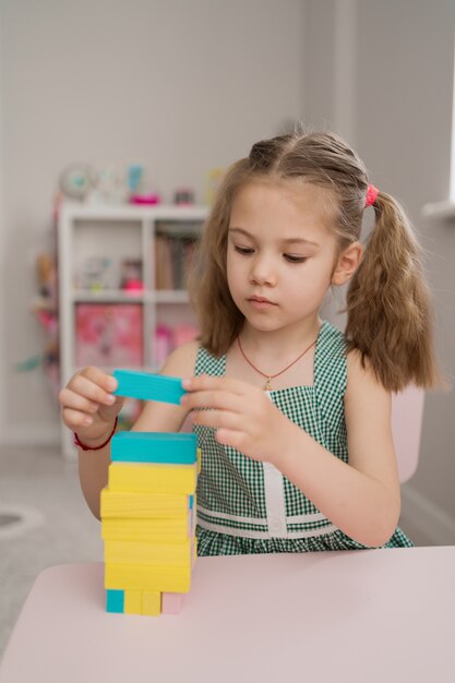 Hermosa niña caucásica jugando con bloques multicolores de madera