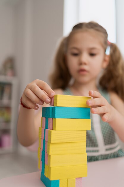 Hermosa niña caucásica jugando con bloques multicolores de madera