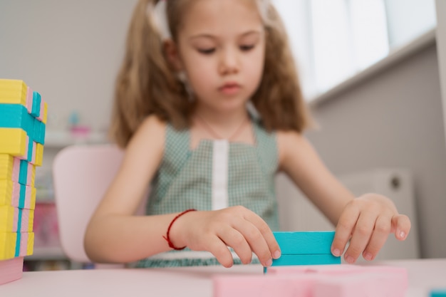 Hermosa niña caucásica jugando con bloques multicolores de madera