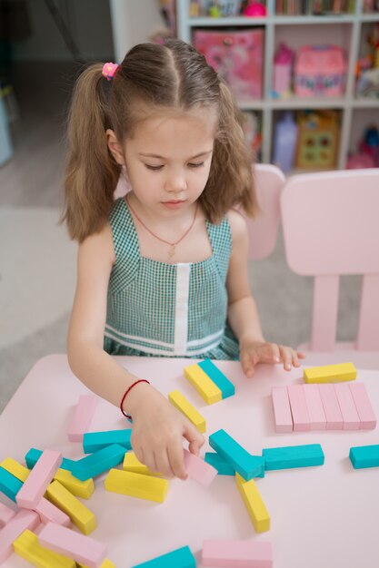 Hermosa niña caucásica jugando con bloques multicolores de madera