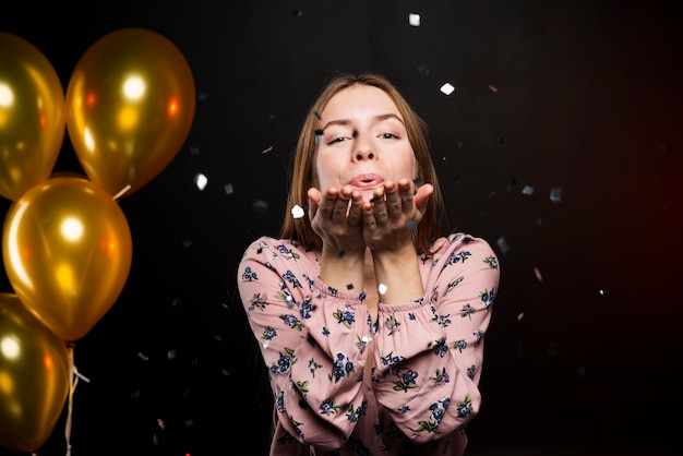 Foto gratuita hermosa niña feliz que sopla un beso y globos de oro