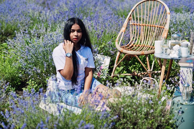 Hermosa niña india sentada en un campo de lavanda púrpura