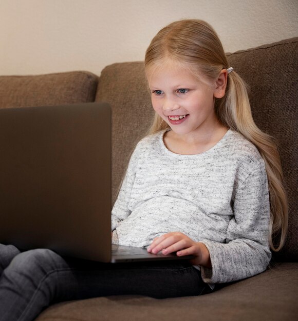 Hermosa niña con laptop en casa