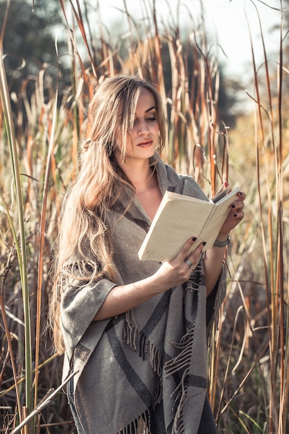 hermosa niña leyendo un libro en el bosque de otoño