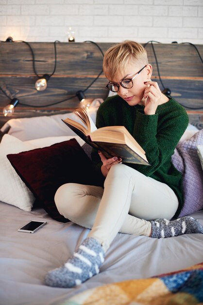 Hermosa niña leyendo un libro en la cama