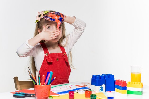 La hermosa niña con las manos en la pintura