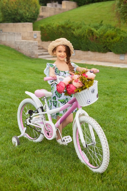 Hermosa niña montando una bicicleta por el parque. Naturaleza, estilo de vida