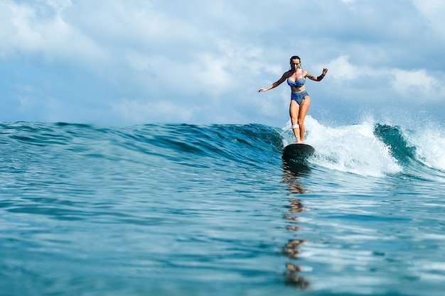 hermosa niña montando en una tabla de surf en las olas