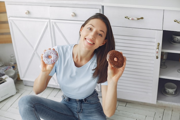 Hermosa niña de pie en una cocina con donut