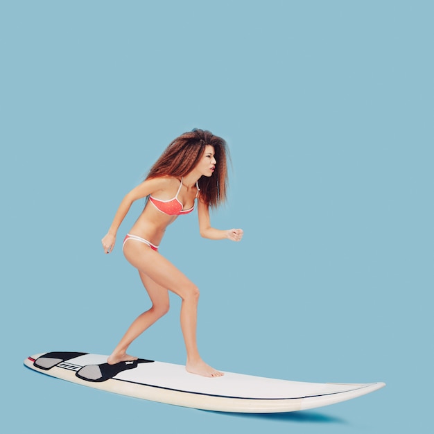 Hermosa niña de pie en la tabla de surf