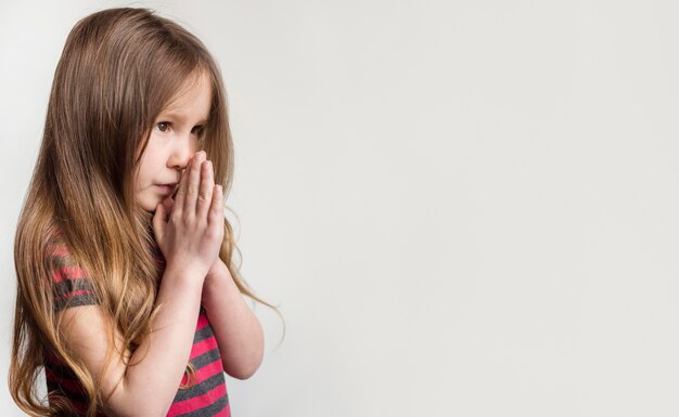 Hermosa niña rezando con espacio de copia