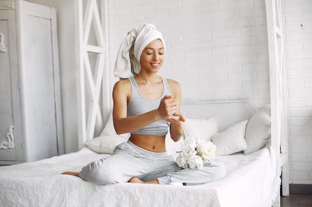 Foto gratuita hermosa niña sentada en una cama con productos de belleza