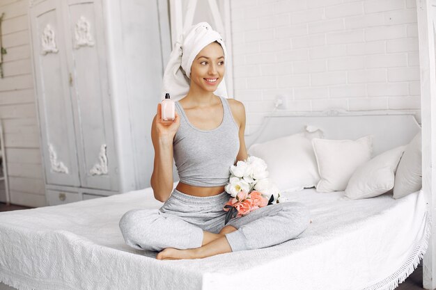 Hermosa niña sentada en una cama con productos de belleza