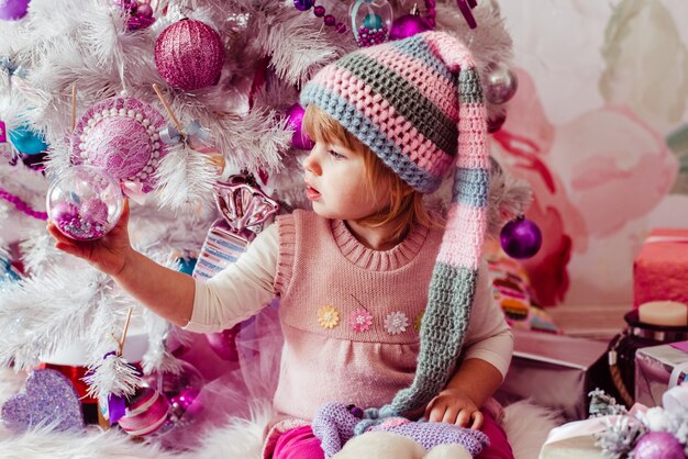 La hermosa niña sentada cerca del árbol de Navidad