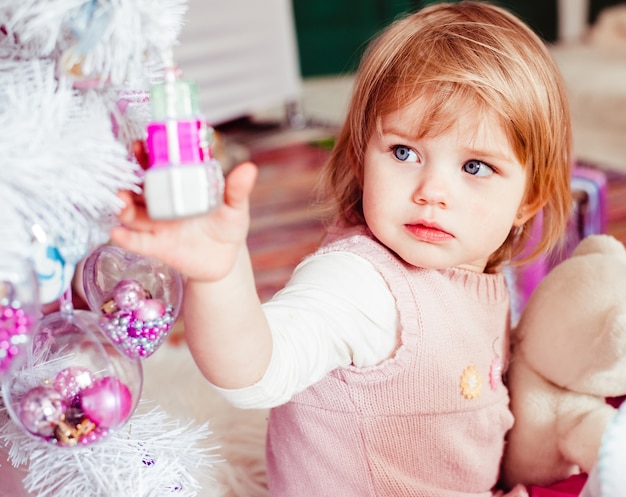 La hermosa niña sentada cerca del árbol de Navidad