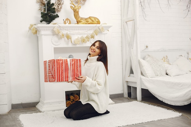 Hermosa niña sentada en una habitación con regalos de navidad