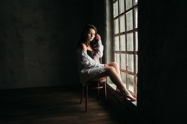 Foto gratuita la hermosa niña se sienta en la silla junto a la ventana