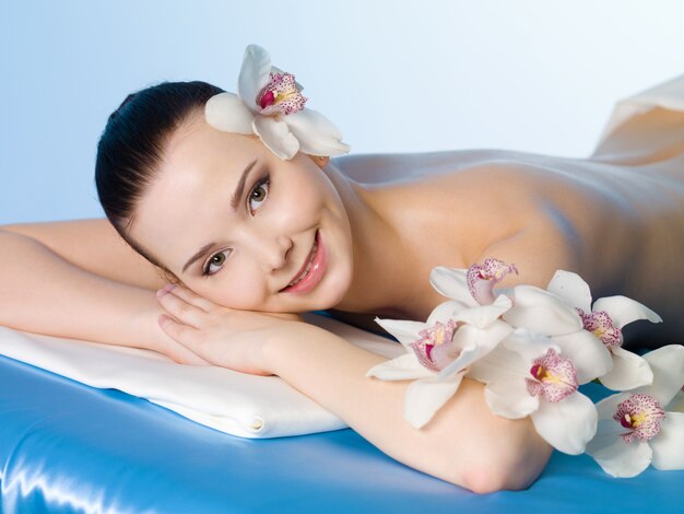 Hermosa niña sonriente relajante en el salón de belleza spa - fondo de color