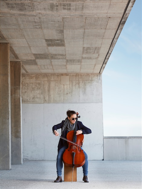 hermosa niña toca el cello con pasión en un ambiente concreto