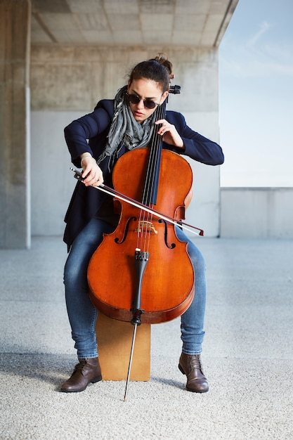 Hermosa niña toca el cello con pasión en un ambiente concreto