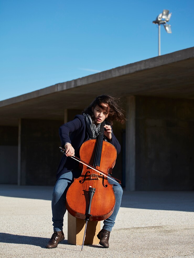 Foto gratuito hermosa niña toca el cello con pasión en un ambiente concreto