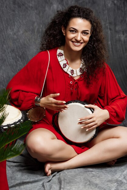 Foto gratuita hermosa niña tocando el tambor en plantas tropicales sobre gris