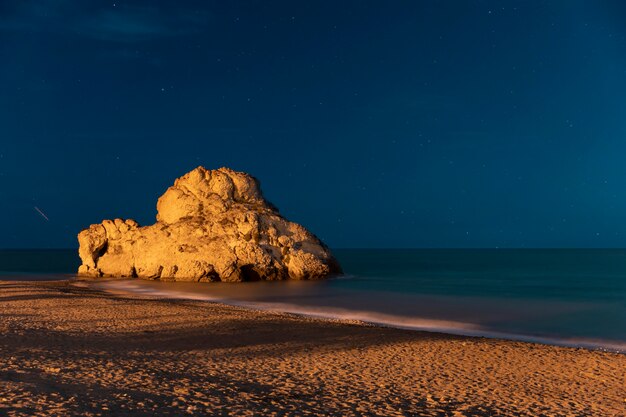 Hermosa noche a la orilla del mar con roca