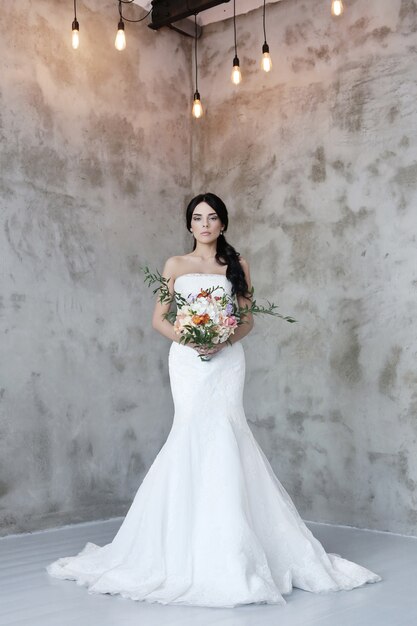 Hermosa novia mujer en vestido de novia con un ramo de flores