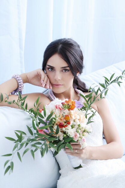 Hermosa novia mujer en vestido de novia con un ramo de flores