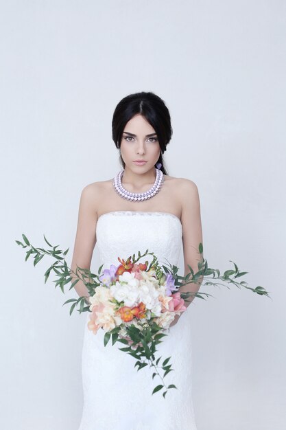 Hermosa novia mujer en vestido de novia con un ramo de flores