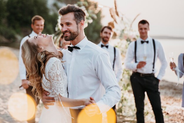 Hermosa novia y el novio en su boda con invitados en la playa