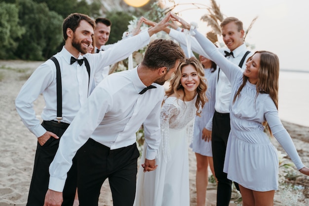 Foto gratuita hermosa novia y el novio en su boda con invitados en la playa