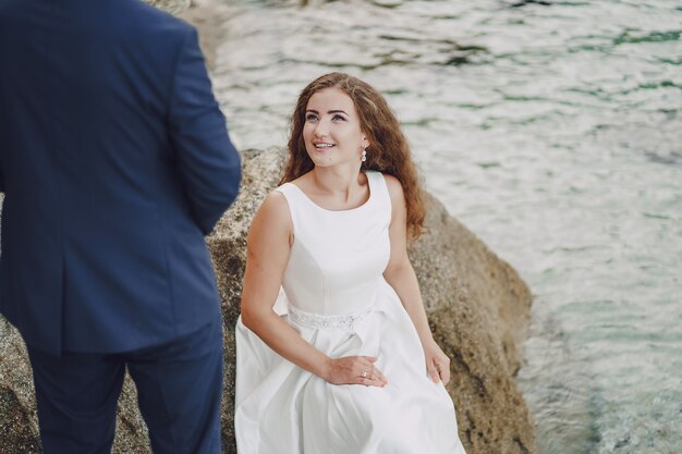 hermosa novia de pelo largo joven en vestido blanco con su joven esposo cerca del río