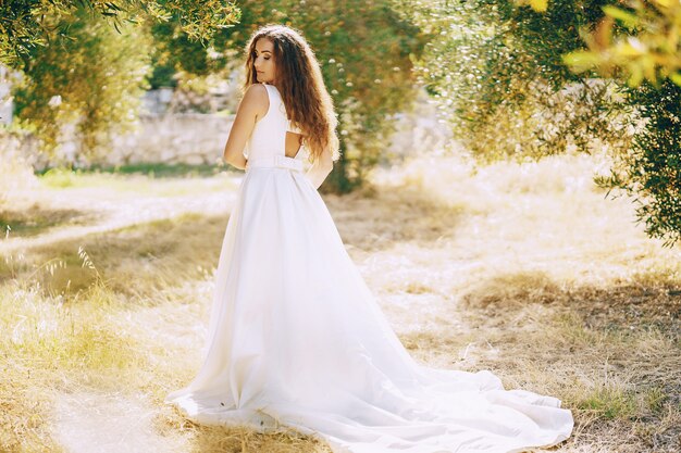 Hermosa novia de pelo largo en un magnífico vestido blanco caminando en la naturaleza