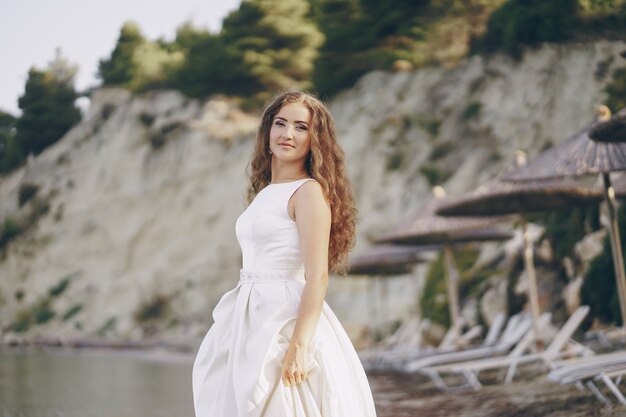 Hermosa novia de pelo largo en un magnífico vestido blanco caminando en una playa