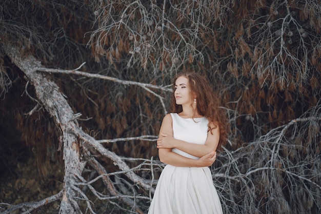 Hermosa novia de pelo largo en un magnífico vestido blanco en la naturaleza